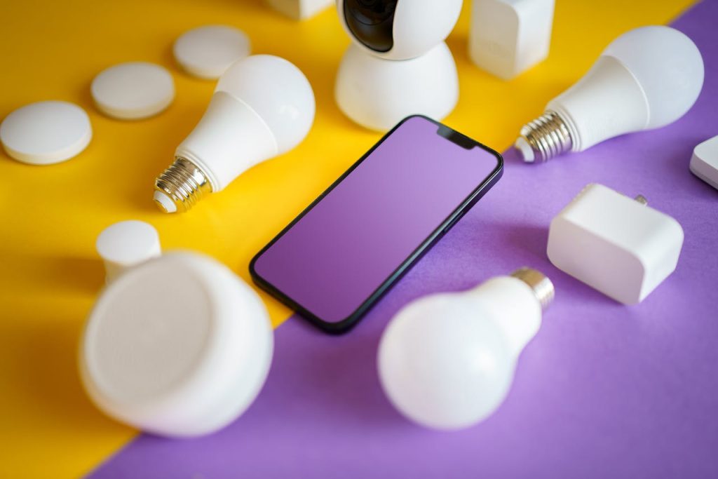 smart-home-electronic-devices-blank-screen-mockup-18275926 Colorful flat lay of smart home devices and smartphone on vibrant background, ideal for technology concepts.